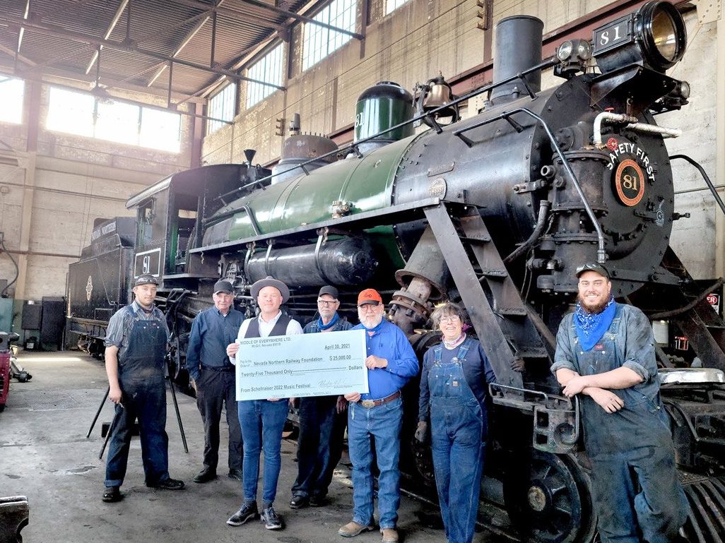 Schellraiser founder Rudy Herndon is pictured in front of a locomotive with Lennox Purinton, Henry Stewart, Gary Hansen, NNR President Mark Bassett, Heidi Still, and John Henry McDonnell.